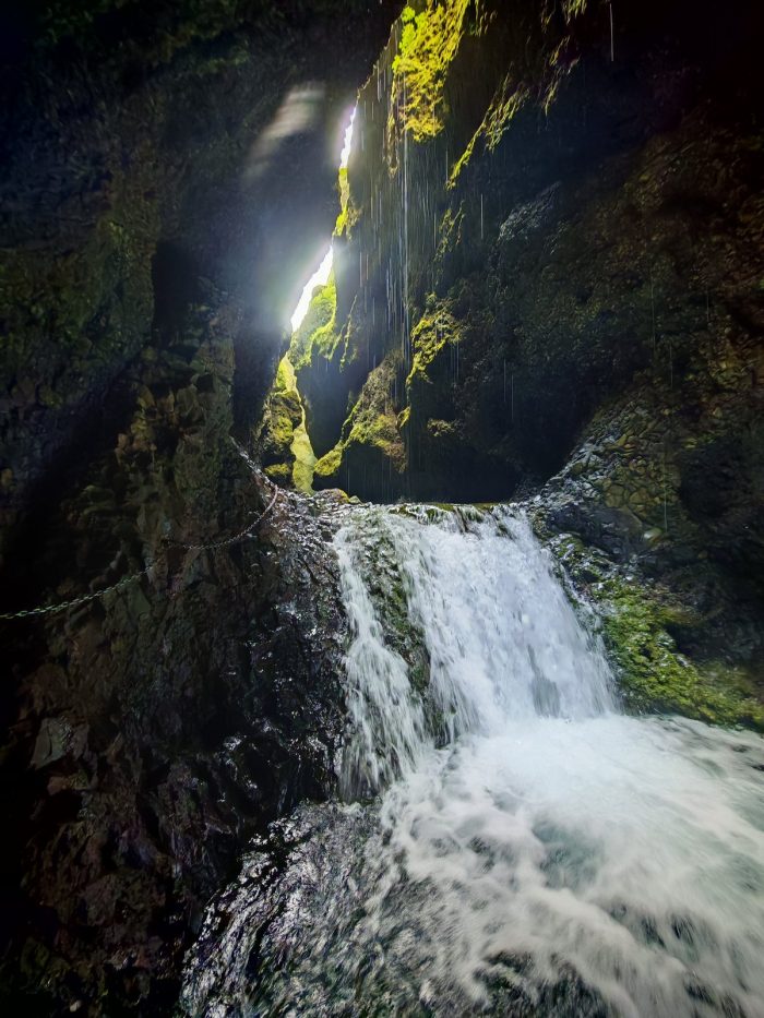 Piccola cascata incassata tra pareti scure, con luce che arriva dall'alto