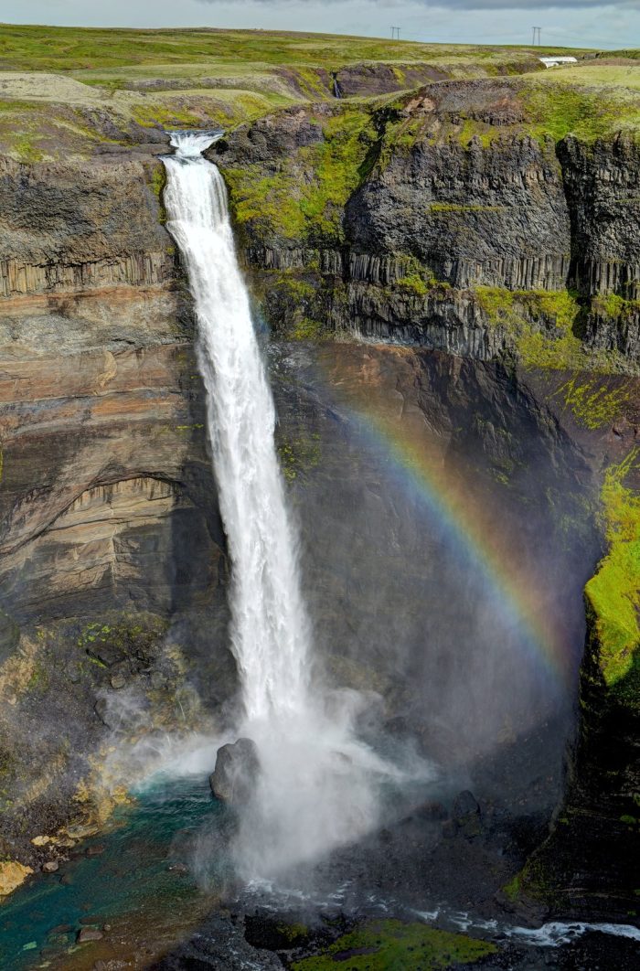 Cascata con arcobaleno, in un ambiente verde e scosceso