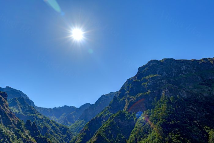 Sole che splende sopra montagne coperte di vegetazione