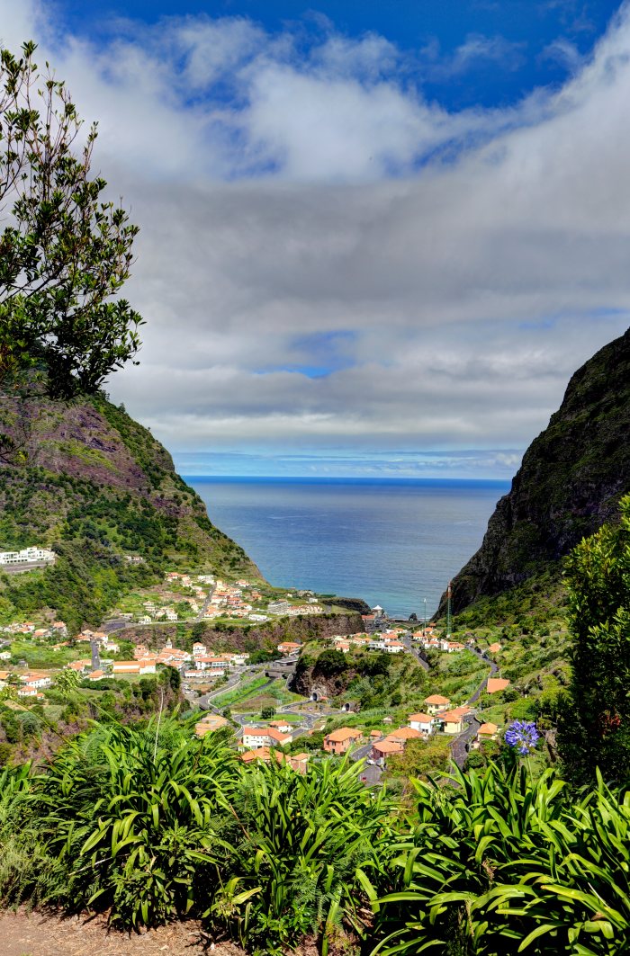 Vista panoramica di un villaggio fra montagne verdi con il mare sullo sfondo